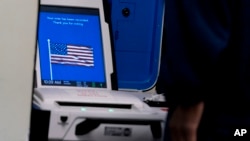 资料照片：在弗吉尼亚州亚历山德里亚的一处提前投票地点，一名选民将其选票输入投票机。(2022年9月26日) 