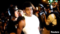 A police officer in riot gear detains a demonstrator protesting against the shooting of Michael Brown, in Ferguson, Missouri August 19, 2014. 