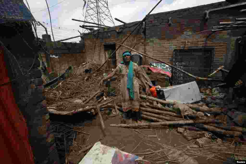 Pakistani woman Mumtaz Bibi stands in her partially-destroyed house following heavy rain in Lahore, Sept. 6, 2014.