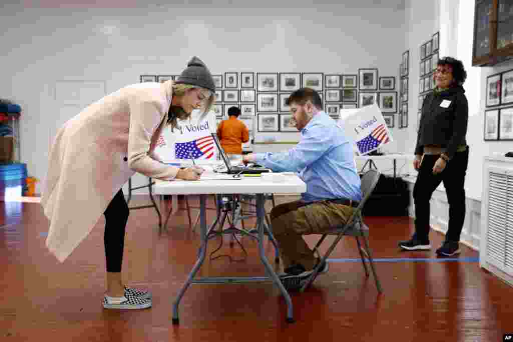 Marie McMahon, left, signs in to vote at a primary polling place, Feb. 29, 2020, in Charleston, S.C. 