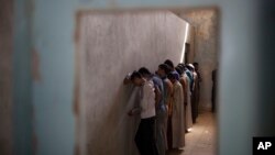 FILE - Displaced men from Hawija stand facing a wall in order not to see security officers, who will try to determine if they were associated with the Islamic State group, at a Kurdish screening center in Dibis, Iraq, Oct. 3, 2017.