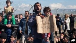 Stranded refugees and migrants protest in front of the wire fence that separates the Greek side from the Macedonian one at the northern Greek border station of Idomeni, Feb. 27, 2016.