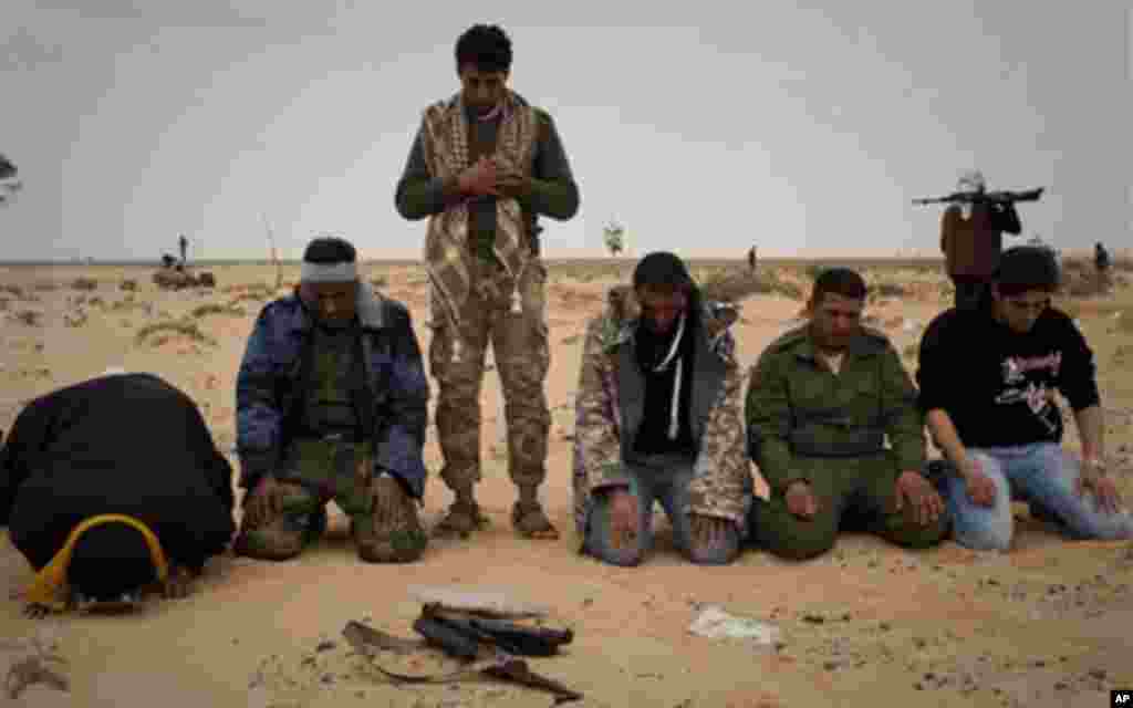 Libyan rebels pray in the desert on the frontline near Sultan, south of Benghazi, Libya, Friday, March 18, 2011. The U.N. Security Council voted Thursday to impose a no-fly zone over Libya and authorize "all necessary measures" to protect civilians from a