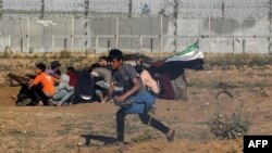 Young Palestinian protesters run away from the border fence during a demonstration east of Gaza City, on May 10, 2019.