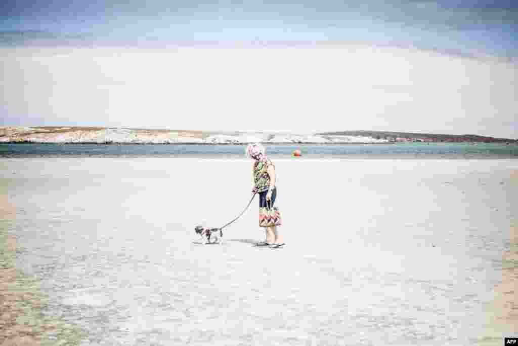 An elderly woman walks her dog on an empty Main Beach in Langebaan, South Africa. President Cyril Ramaphosa announced new lockdown measures to limit the spread of COVID-19. 