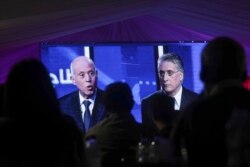 People watch a televised debate between presidential candidates Kais Saied, left, and Nabil Karoui, on the last day of campaigning before the second round of the country's presidential elections, in Tunis, Tunisia, Oct. 11, 2019.