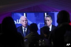 People watch a televised debate between presidential candidates Kais Saied, left, and Nabil Karoui, on the last day of campaigning before the second round of the country's presidential elections, in Tunis, Tunisia, Oct. 11, 2019.