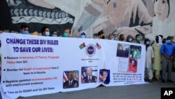 FILE - Former Afghan interpreters hold placards during a demonstrations against the U.S. government, in front of the U.S. Embassy in Kabul, June 25, 2021. The House voted July 22 to allow in Afghans who worked alongside Americans in the war.