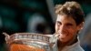 Spain's Rafael Nadal bites the trophy after winning the final of the French Open tennis tournament against Serbia's Novak Djokovic at the Roland Garros stadium, in Paris, France, Sunday, June 8, 2014. 