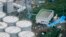 An aerial view shows workers wearing protective suits and masks working atop contaminated water storage tanks at Tokyo Electric Power Co. (TEPCO)'s tsunami-crippled Fukushima Daiichi nuclear power plant in Fukushima, Aug. 20, 2013.