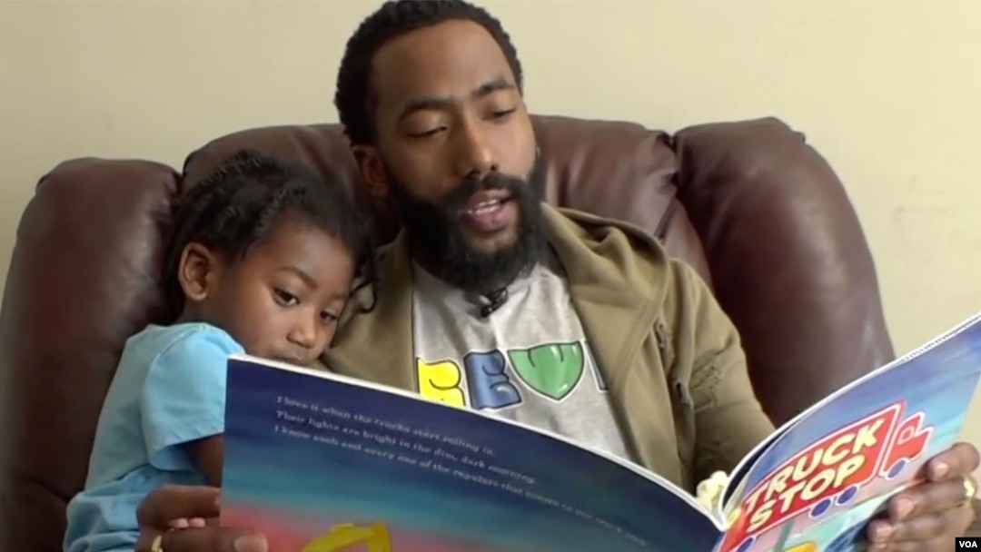 Joshua Clark le lee a su hijo un libro proporcionado por el DC Books from Birth Program que ofrece libros gratuitos para niños a los residentes de Washington, DC.
