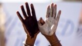 An African asylum seeker, who entered Israel illegally via Egypt, uses handcuffs and raises up his hands painted in black and white during a protest in front of the Israeli Interior Ministry in the Mediterranean coastal city of Tel Aviv after several days of mass protests against Israel&#39;s immigration policies.
