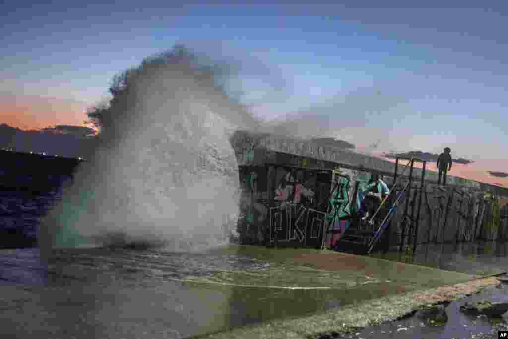 A wave hits a wave-lashed breakwater during a windy afternoon in the southern Athens coastal suburb of Flisvos, Greece, Feb. 8, 2021.