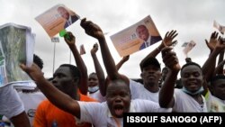 Des supporters brandissant des drapeaux soutenant Alassane Ouattara acclament le président de la Côte d'Ivoire lors de son discours au stade Félix Houphouët-Boigny, le 22 août 2020 à Abidjan, à l'occasion de son investiture par le RHDP. (Photo by Issouf SANOGO / AFP)