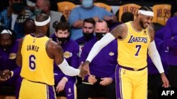 LeBron James and Carmelo Anthony of the Los Angeles Lakers touch hands in a break of action against the Golden State Warriors during their NBA season opener in Los Angeles, California on October 19, 2021. (Photo by Frederic J. BROWN / AFP)