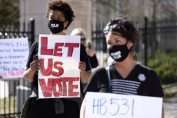 FILE - Protesters gather outside of the Georgia State Capitol in Atlanta to protest a bill which would place tougher restrictions on voting in Georgia, March 4, 2021.