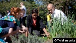 La primera dama junto a su asesor en las iniciativas de alimentación suladable, Sam Kass y una estudiante en el jardín presidencial.