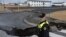 A police officer stands by the crack in a road in the fishing town of Grindavik, Iceland, on Nov. 15, 2023. The town was evacuated because of the threat of a volcanic eruption.