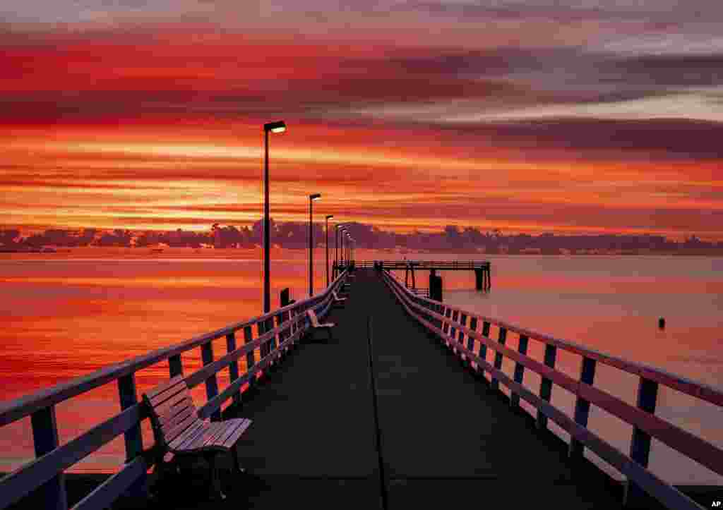 A pier is lit in the sunrise in Timmendorfer Strand at the Baltic Sea, northern Germany.