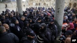 Israeli police stand at the door to the Dome of the Rock mosque confronted by Palestinians, Jan. 14, 2019. 