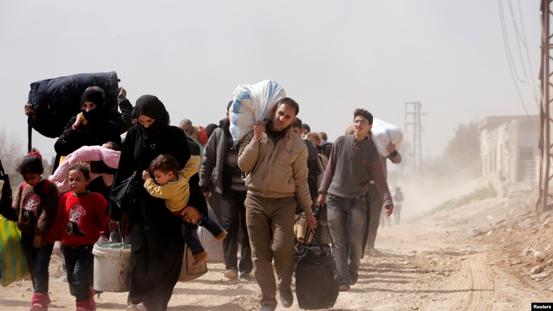Warga berjalan dengan harta benda mereka saa tmelarikan diri dari Kota Hammouriyeh, yang dikuasai pemberontak, di Desa Beit Sawa, timur Ghouta, Suriah, 15 Maret 2018.