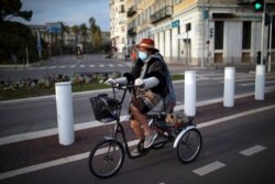 A Nice resident and her dog go for a bike ride during virus-related confinement in Nice, southern France, Feb. 27, 2021. Nice and the surrounding coastal area will be under weekend lockdowns for at least two weeks.