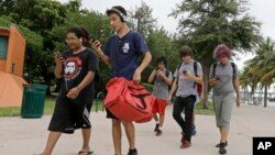 Sekelompok pemain Pokemon Go mengecek ponsel mereka sambil berjalan mencari Pokemon di Taman Bayfront, Miami, AS (12/7). (AP/Alan Diaz)