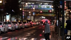 Seorang pria berjalan melintasi persimpangan jalan yang sepi, menuju stasiun kereta di Tokyo, Jumat, 5 Maret 2021. (AP Photo/Hiro Komae). Keadaan darurat untuk Tokyo dan sekitarnya diperpanjang hingga dua pekan mendatang.