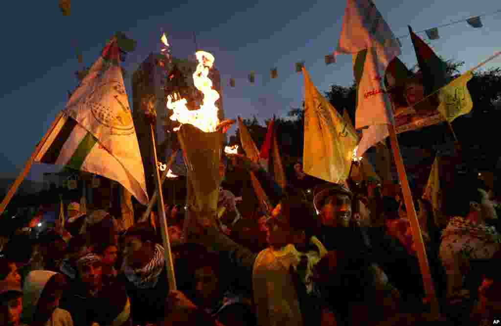 Palestinians hold torches and posters of late Palestinian President Yasser Arafat and late Hamas founder and spiritual leader Sheik Ahmed Yassin, during celebrations marking the 49th anniversary of the Fatah movement in Gaza City.