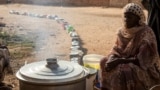 (FILE) A Sudanese woman from a community kitchen as empty pots are seen lined up to receive food, in Omdurman, Sudan, September 19, 2024. 