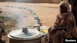 (FILE) A Sudanese woman from a community kitchen as empty pots are seen lined up to receive food, in Omdurman, Sudan, September 19, 2024. 