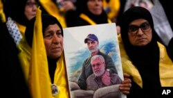 FILE - A Hezbollah supporter shows portrait of slain Iran's Quds force General Qassem Soleimani, top, and Abu Mahdi al-Muhandis, deputy commander of Iran-backed militias in Iraq known as the Popular Mobilization Forces, in the southern suburbs of Beirut, Lebanon, January 3, 2024.