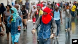 A hooded protester, equipped with stones, takes part in a protest against fuel shortages and to demand the resignation of President Jovenel Moise, in Port-au-Prince, Haiti, Sept. 20, 2019. 