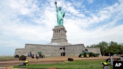 In this June 26, 2013 photo provided by the National Park Service, workers on Liberty Island install sod around the national monument which is set to re-open on the 4th of July, in New York. 