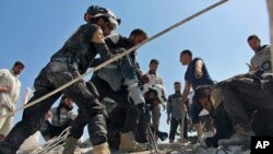 FILE - This photo provided by the Syrian Civil Defense White Helmets shows Civil Defense workers using machinery to search through the rubble after airstrikes hit in Khan Sheikhoun, in the northern province of Idlib, Syria, Sept, 24, 2017. 