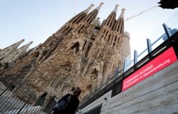 A tourist records with her mobile phone the landmark Sagrada Familia basilica, which stopped receiving visitors due to the coronavirus outbreak in Barcelona, Spain, March 13, 2020.