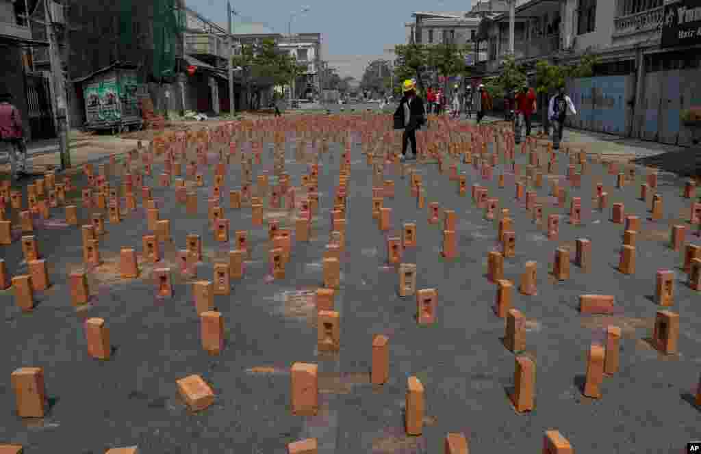 An anti-coup protester walks along a road studded with bricks, in Mandalay, Myanmar.