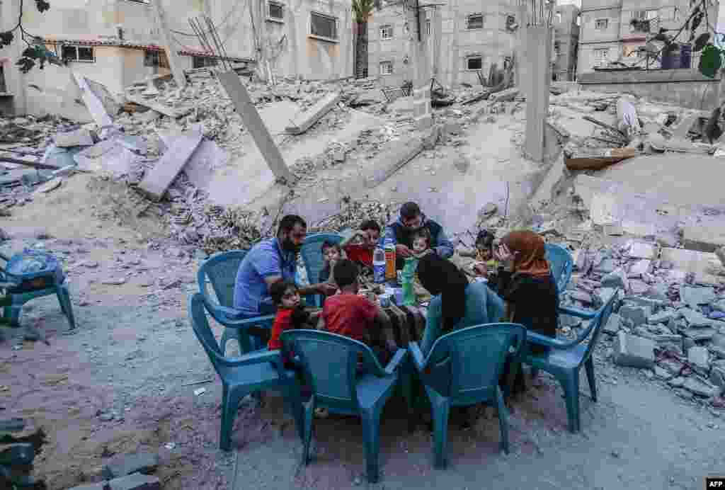 Keluarga Palestina berbuka puasa di samping rumah mereka yang hancur dalam konflik dua hari di Rafah, selatan Jalur Gaza, 8 Mei 2019. (Foto: AFP)