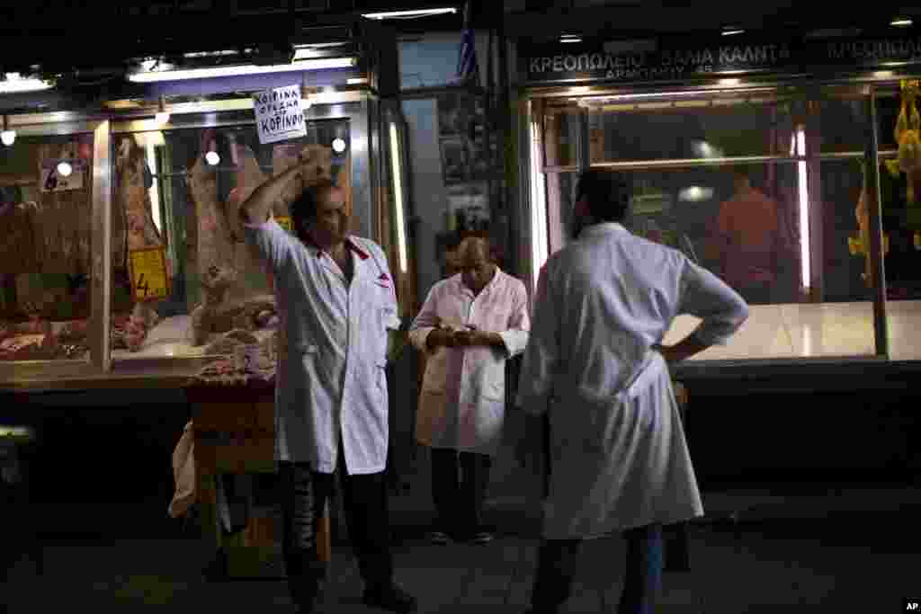 Butchers wait for customers at a meat market in central Athens, July 3, 2015.