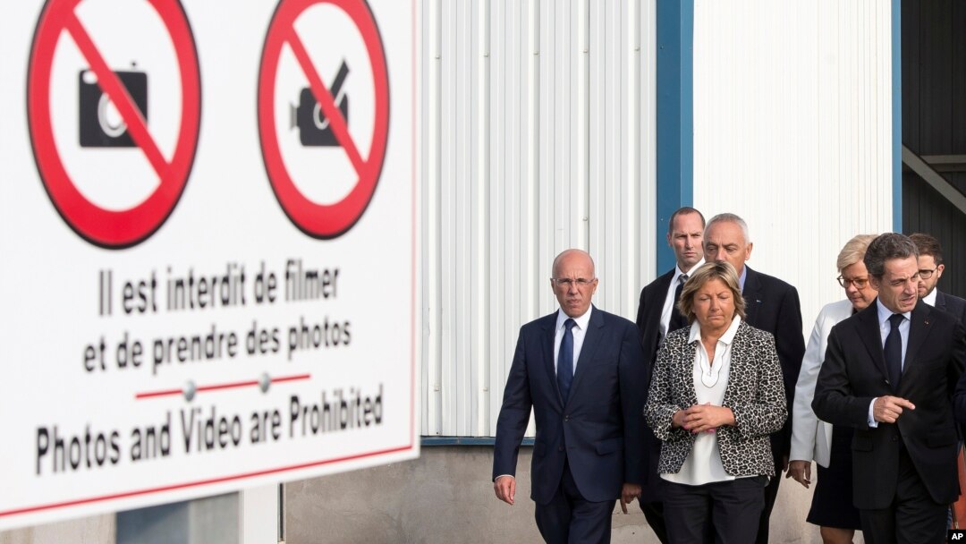 Former French President and candidate for the right-wing Les Republicains party primary Nicolas Sarkozy, right, flanked by Calais Mayor Natacha Bouchart, center, walks during his visit at Calais harbour, northern France, Sept. 21, 2016. 