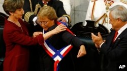 Michelle Bachelet recibe la banda presidencial de manos de la presidenta de la Cámara Alta, Isabel Allende Bussi. A la derecha aplaude el expresidente Sebastián Piñeira.