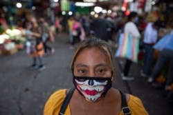 A woman wearing a mask against the spread of the new coronavirus poses for a photo at La Terminal market in Guatemala City, May 21, 2020.