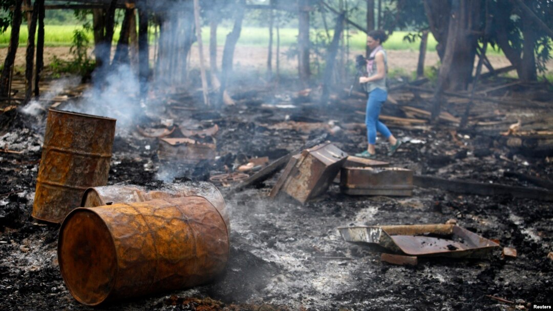 Seorang wartawan tengah berjalan di antara puing-puing rumah yang hangus terbakar di desa Shwe Lay, di pinggir wilayah Thandwe, negara bagian Rakhine, Burma (2/10).
