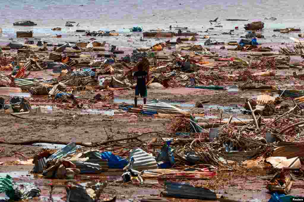 A boy carries a roofing sheet on the beach in the aftermath of Cyclone Chido, in Passamainty, Mayotte.