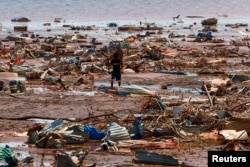 A boy carries a roofing sheet on the beach in the aftermath of Cyclone Chido, in Passamainty, Mayotte, Dec. 20, 2024.