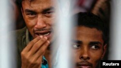 FILE - Rohingya people from Myanmar, who were rescued from human traffickers, react from inside a communal cell at Songkhla Immigration Detention Centre, near Thailand's border with Malaysia.