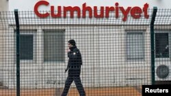 FILE - A private security employee stands guard at the entrance of the offices of daily newspaper Cumhuriyet, in Istanbul, Turkey.