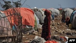 FILE - A Somali woman carries wood to make a shelter in an internally displaced people (IDP) camp, Dec. 18, 2018.