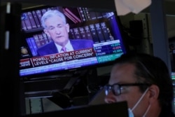 FILE - A screen shows Federal Reserve Chair Jerome Powell speaking as a trader works inside a post on the floor of the New York Stock Exchange in New York City, August 27, 2021.