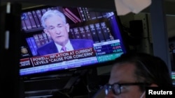 FILE - A screen shows Federal Reserve Chair Jerome Powell speaking as a trader works inside a post on the floor of the New York Stock Exchange in New York City, August 27, 2021. 